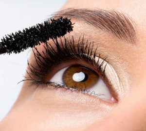 girl applies black mascara on her lashes