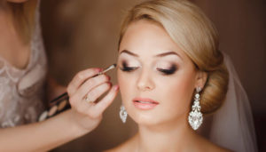 makeup artist makes wedding makeup to a bride