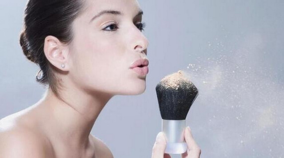 girl applies loose powder with a natural kabuki brush