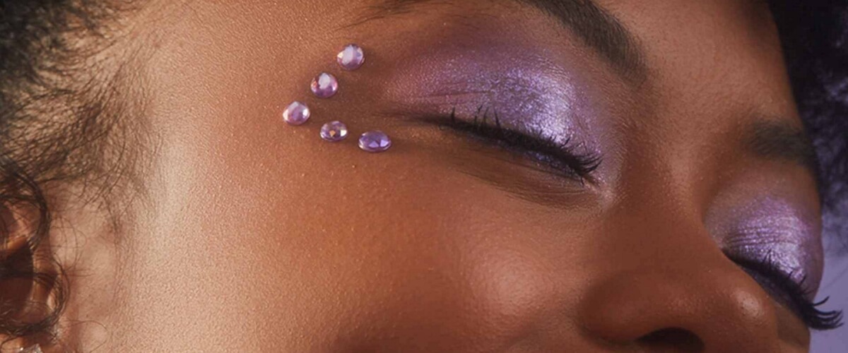 Artistic makeup with lilac glitter eye shadow and purple pearls