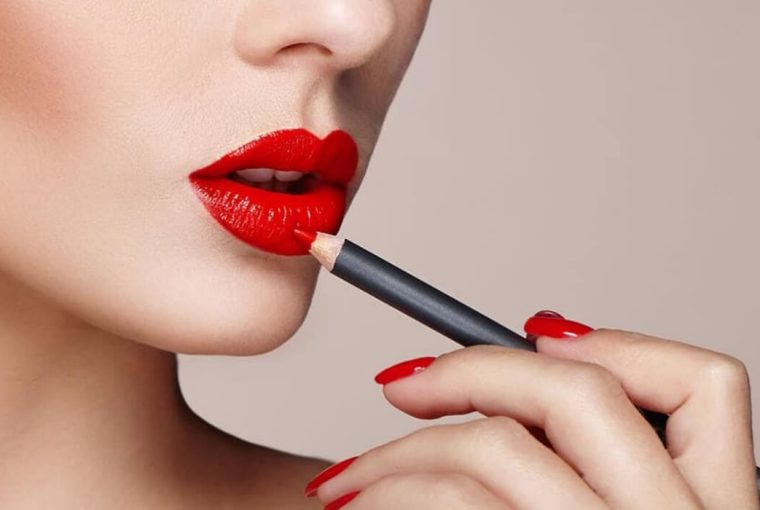A woman applying bright red lip liner