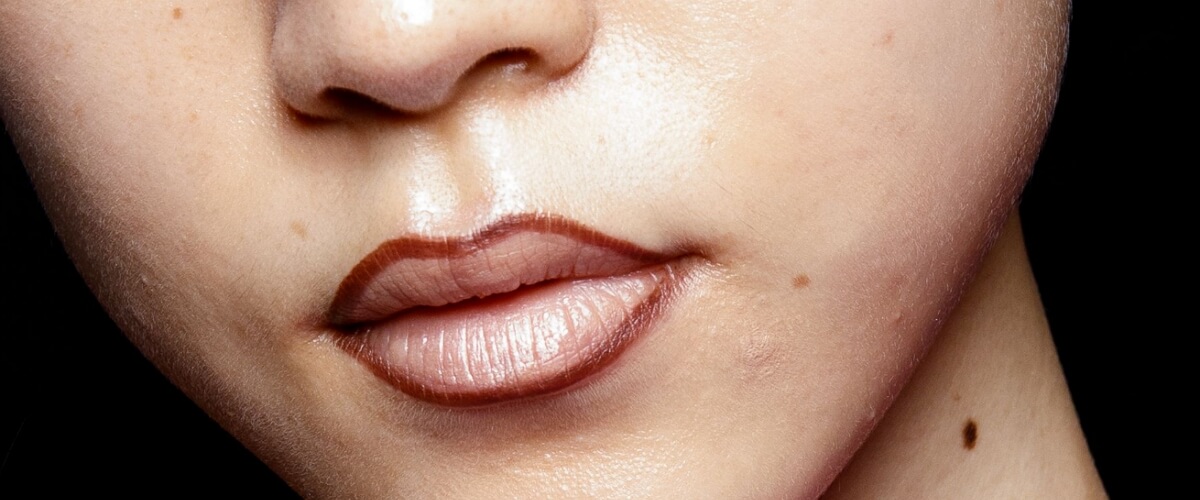 A woman with just dark brown lip pencil outline on her lips