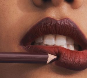 Lady applies brown lipstick on her lips