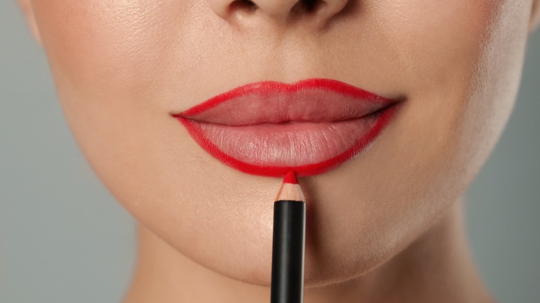 woman applying red lip pencil