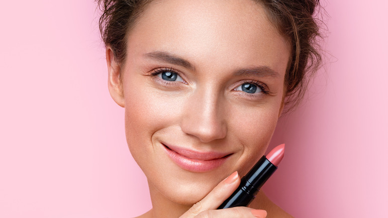 woman holding pink lipstick 