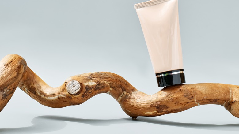 A makeup tube balanced on a piece of wood