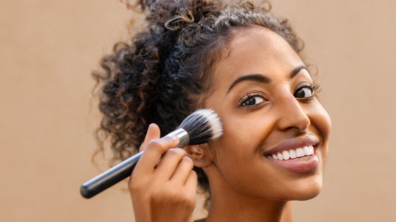 Woman applying makeup with a brush