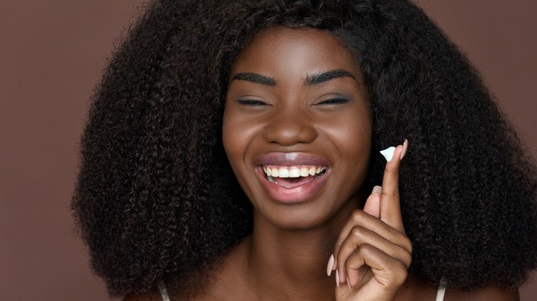Woman laughing with a little bit of moisturizer on her finger
