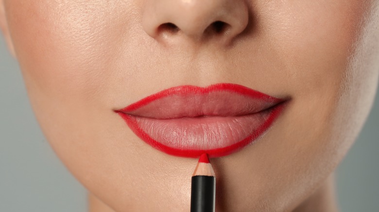 woman applying red lip liner