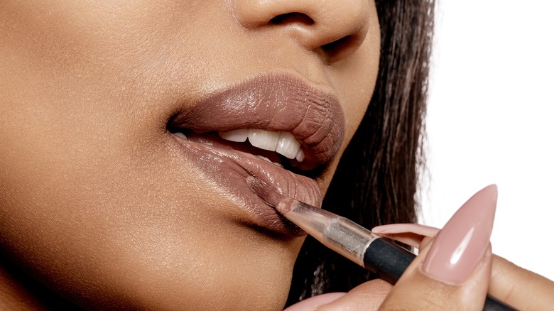 woman applying brown lipstick