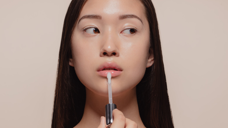 Asian woman applying lip gloss